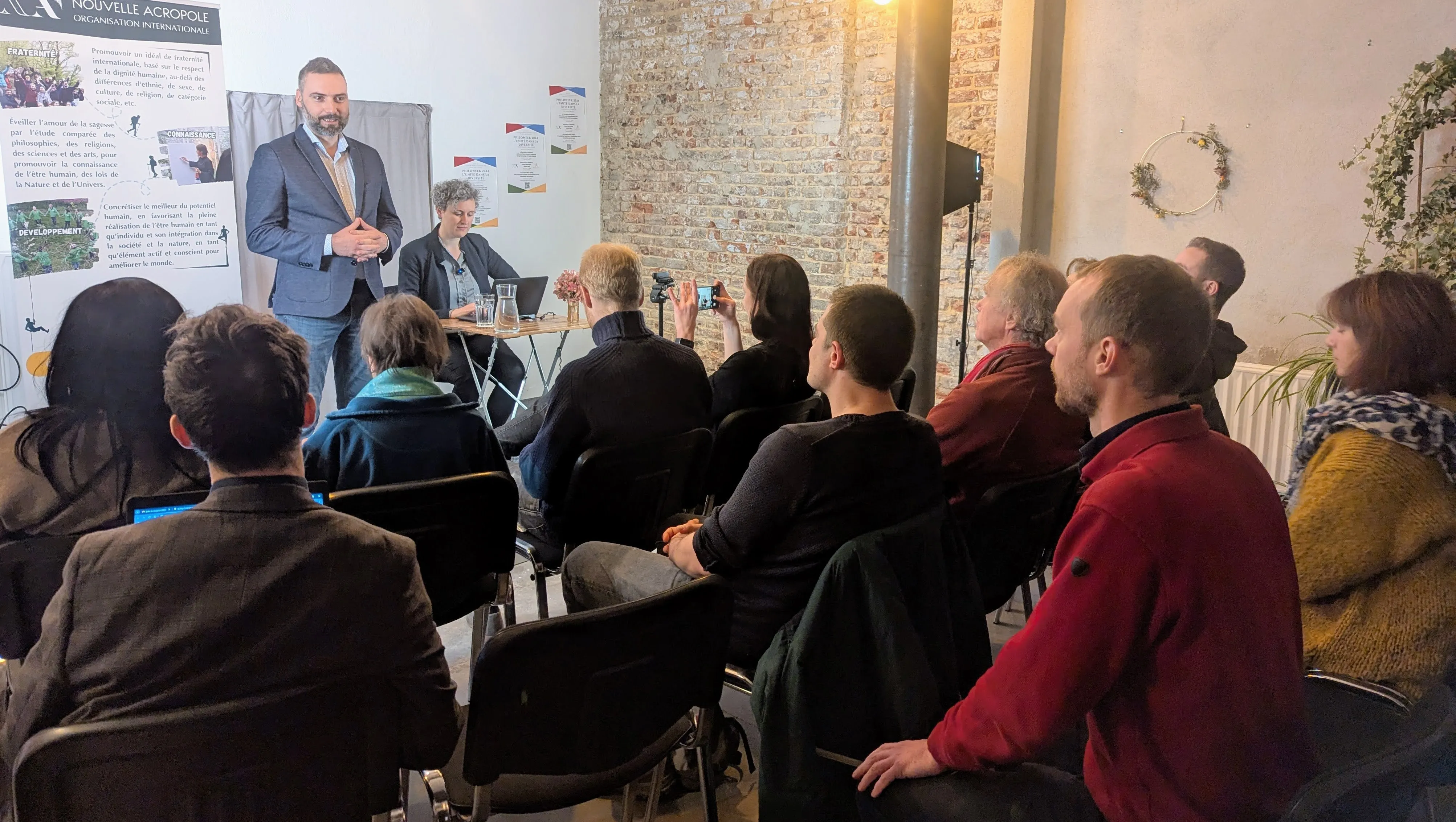 Conférence de philosophie pratique à Bruxelles : un intervenant s'adresse aux participants réunis en salle.
